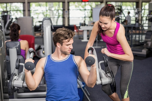 Trainervrouw die de atletische mens in gymnastiek helpen