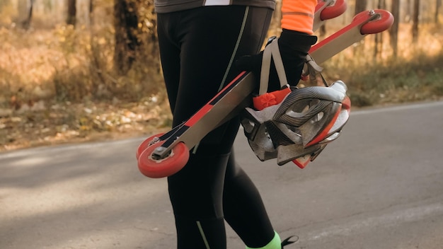 Allenare un atleta sul giro di biathlon dei pattinatori a rotelle sugli skiroll con i bastoncini da sci nell'hel