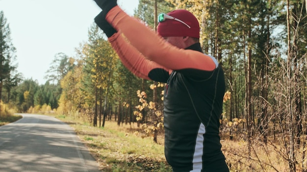 ローラースケート選手でアスリートをトレーニングするバイアスロンは、ヘルメットにストックを入れてローラースキーに乗る秋のトレーニングローラースポーツスケートに乗る大人の男性アスリートがトレーニングを行う