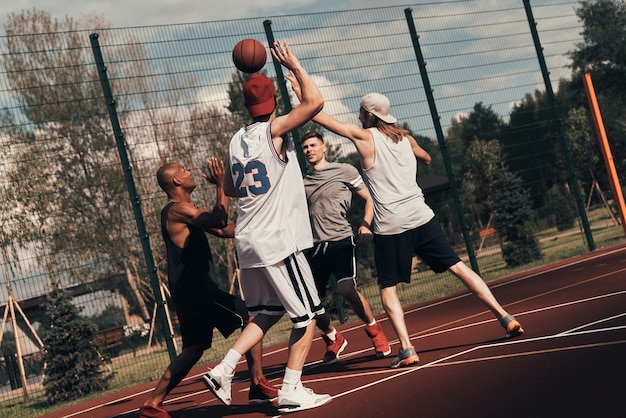 Training to become the best. Group of young men in sports clothing playing basketball while spending time outdoors