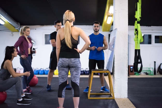 Corso di formazione.gruppo di giovani atleti che ricevono istruzioni dall'allenatore prima dell'esercizio in palestra cross fitness