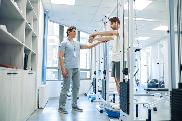 Photo training device doctor halping a patient to workout on a training device