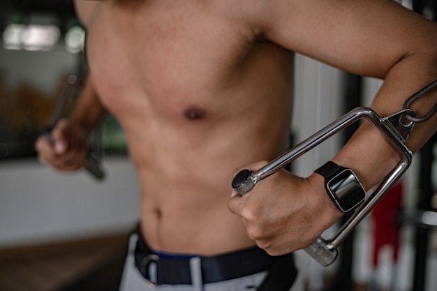 Training gym concept a muscled male teenager using a gym equipment repeating pushing forward for developing his breast.