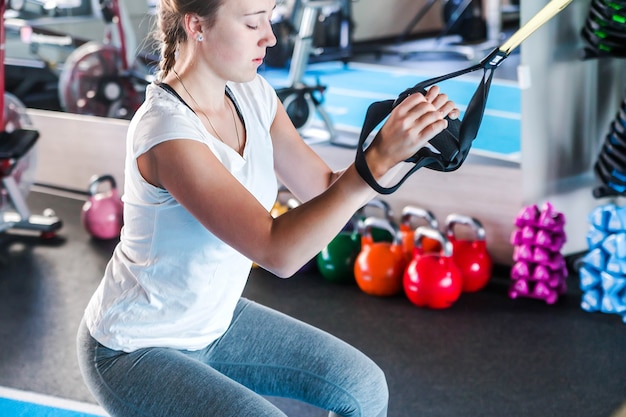 Training in the gym. Fitness girl to build up muscles. Fitness trainer to warm up. Horizontal photo