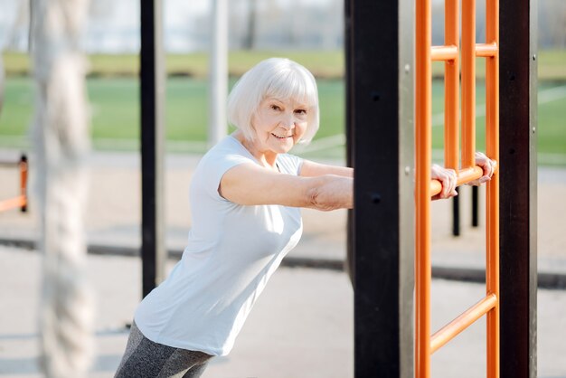 一生懸命トレーニング。スポーツ服を着て野外で運動する嬉しい金髪の女性