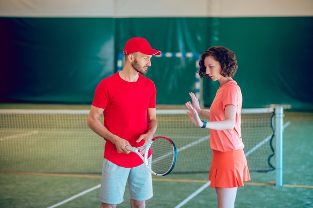 Training. Man in een rode pet en met een racket aan het trainen met zijn coach