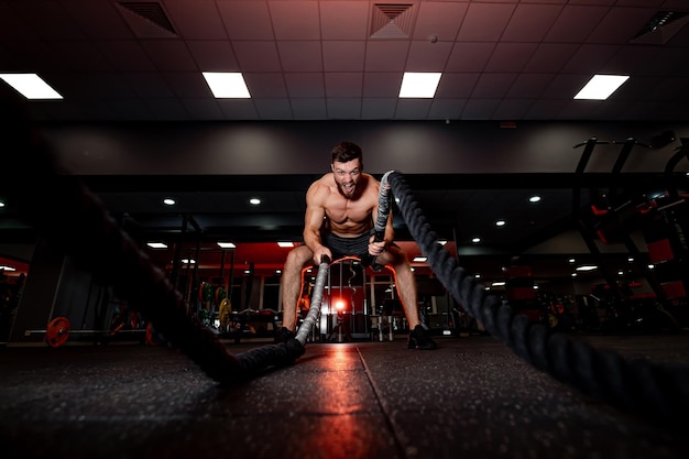 Training muscular male person in the gym Young male athletic man working out in gym