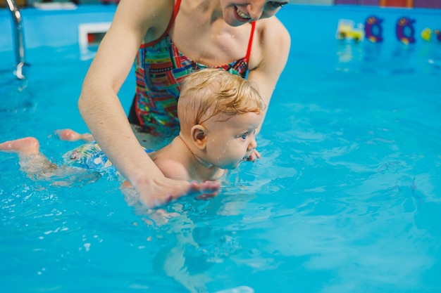 Training of a newborn baby in the pool with a swimming coach A pool for babies Child development A small child learns to swim in the pool