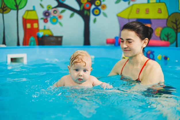 Training of a newborn baby in the pool with a swimming coach A pool for babies Child development A small child learns to swim in the pool