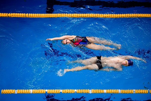 Training of professional swimmers. Athletes swim on their backs in the pool.