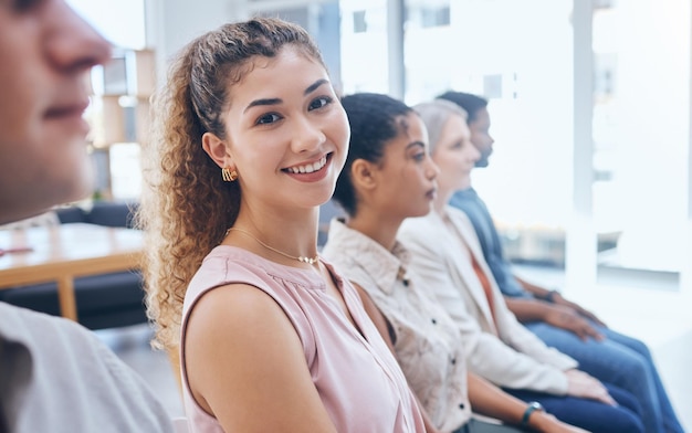 Team di formazione e donna in un felice incontro di lavoro con un sorriso seduto a una conferenza o a un seminario convegno per il coaching ritratto di una dipendente che sorride tra il pubblico a un seminario di gruppo