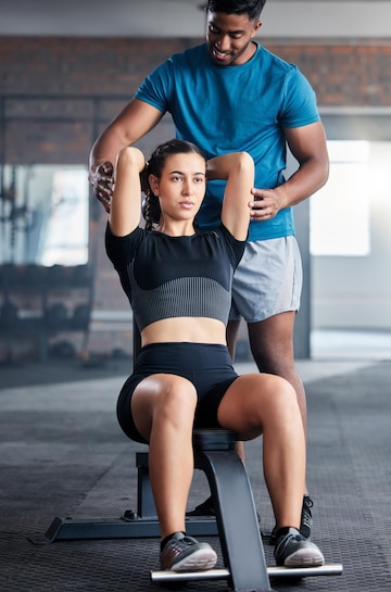 Premium Photo  Female personal trainer helping woman doing exercises in  the gym.