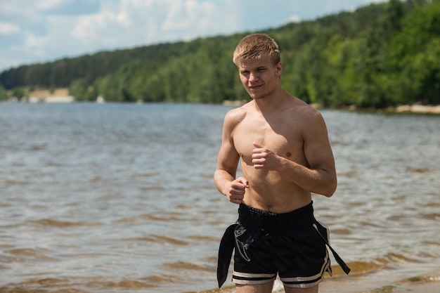 Training of a young man on the beach. A young man on a morning jog