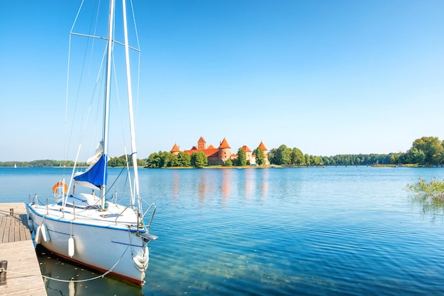 Trakai castle on island lake with white yacht in Lithuania