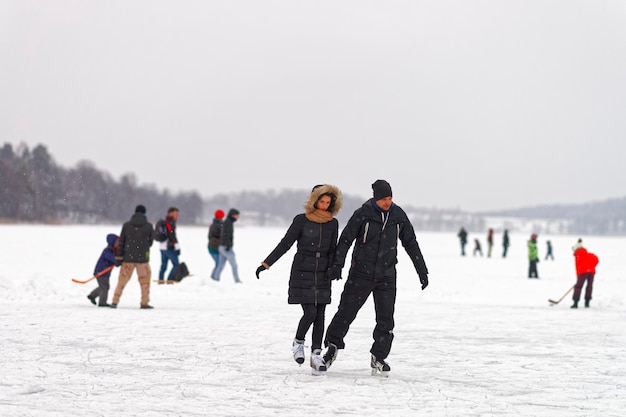 트라카이, 리투아니아 - 2016년 1월 17일: 눈 덮인 스케이트장에서 젊은 부부 아이스 스케이팅 Trakai. 스케이팅에는 스케이트를 사용하여 얼음 위를 여행하는 모든 활동이 포함됩니다. 선택적 초점