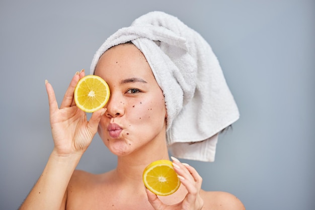 Trakteer uzelf op wat vitamine C Shot van een jonge vrouw die halve citroen vasthoudt tegen een grijze achtergrond