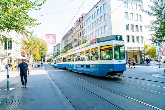 スイスのチューリッヒの歩道を人が歩く間、路面電車がバーンホフシュトラーセの中心部を走っています。