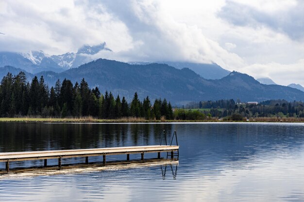 Спокойный пейзаж с пустым причалом у горного озера в Баварских Альпах, Германия