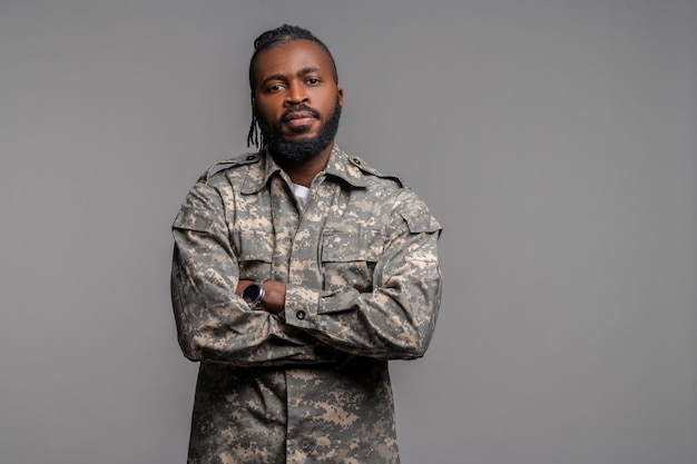 Tranquil male in a khaki uniform standing by the wall