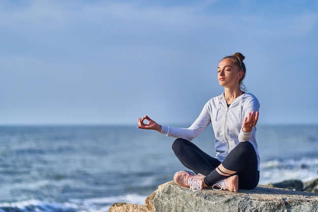 照片的一个女人在lotus冥想位置和放松在悬崖