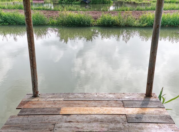 農村地域の池に対する木の板の床の静かな風景