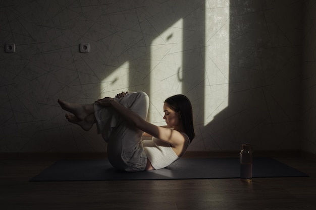 tranquil woman lying on mat in Wind relieving pose or Apanasana and doing yoga