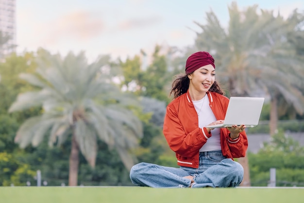 The tranquility of the park serves as an idyllic workspace for a student girl who uses her laptop to research learn and grow