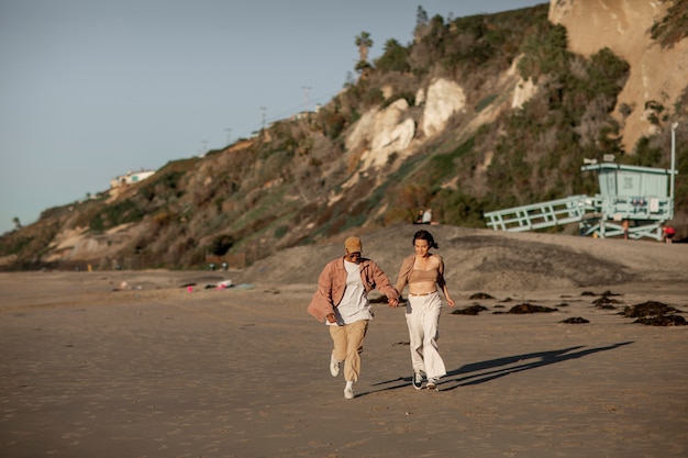 Foto coppia trans che corre sulla spiaggia e si tiene per mano