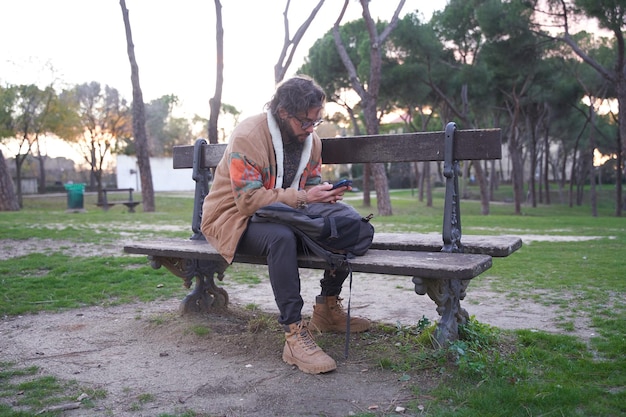 Trans man sitting in a park chatting on his cell phone