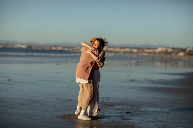 Foto trans paar knuffelen op het strand bij zonsondergang