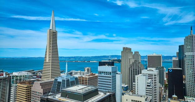 Transamerica pyramid aerial beside downtown skyscrapers with cloudy blue sky and san francisco bay