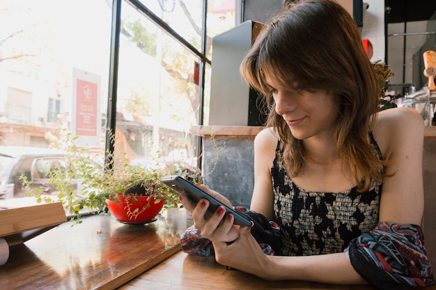 Transgender woman alone sitting using the phone sitting in a restaurant