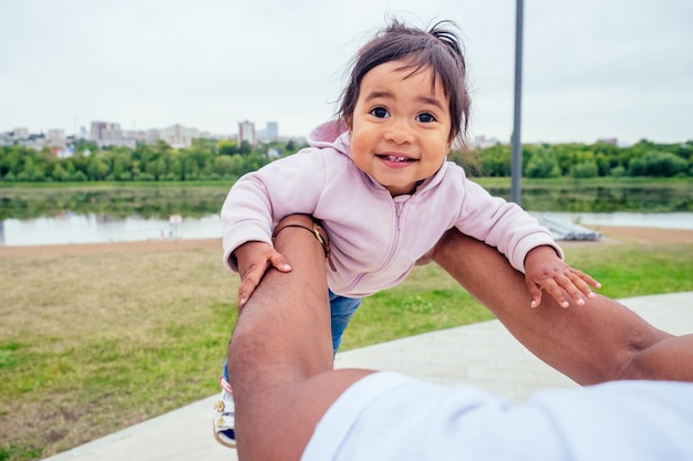 transnational interracial afro father spinning around circles at the park mixed race baby girl .