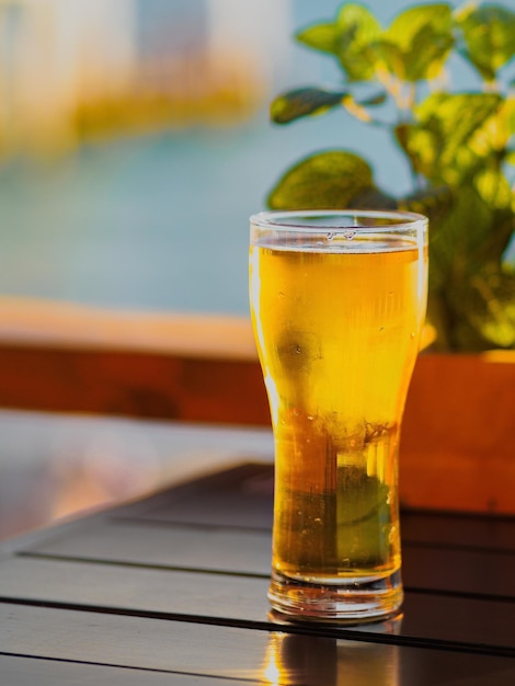 Transparant glas bier staat op een houten tafel in een open café.