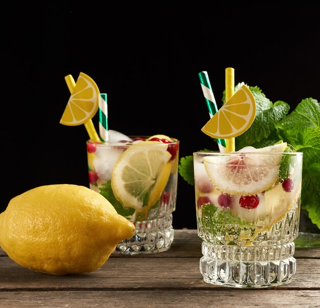 Transparant glas met limonade en stukjes ijs, rode bessen