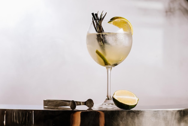 Transparante alcoholcocktail met limoen en ijs op de rokerige achtergrond