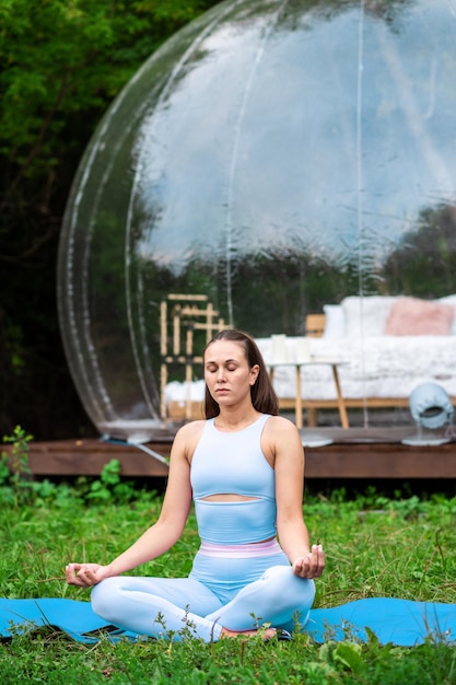 Transparante bubbeltent en vrouw die yoga doet bij glamping