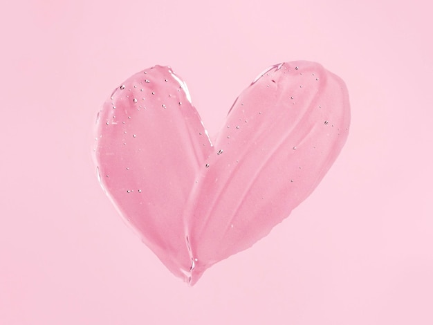 Transparante cosmetische gel hartvorm op roze bg