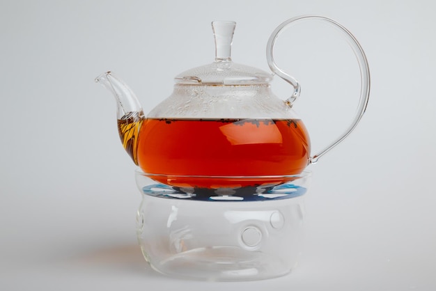 Foto transparante glazen theepot met thee geïsoleerd op witte achtergrond
