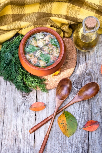 Transparante soep in een aarden pot met crackers en vegetarische dille. bovenaanzicht.