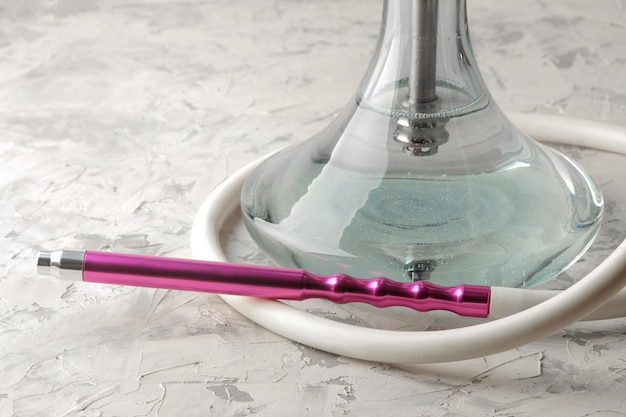 Transparante waterpijp met een mooi roze mondstuk op een lichte achtergrond waterpijpaccessoires