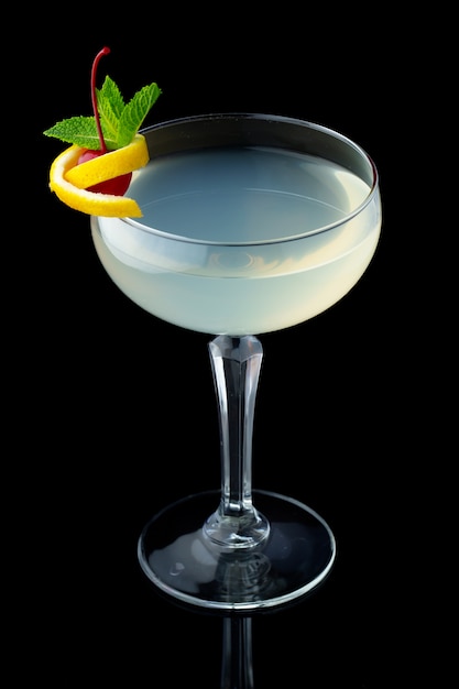 Прозрачный алкогольный коктейль с мятой и вишней на черном фоне