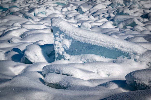 Transparent blue ice floes piled in ice hummocks against a blue sky on a sunny day. Unusual winter landscape of the frozen lake Baikal. Natural cold background. Siberia, Russia.