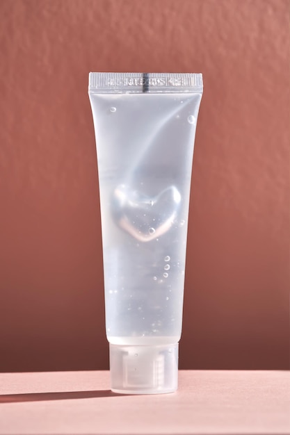 Transparent bottle of cosmetic gel on a peach background