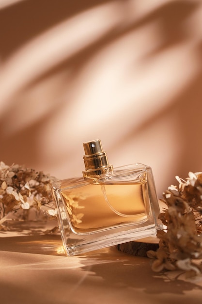 Transparent bottle of perfume on a beige background Trending concept in natural materials with dry plant Womens and mens essence