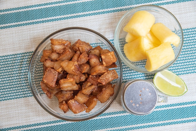 Transparent bowl with crackling with manioc, lemon and salt on the striped background 