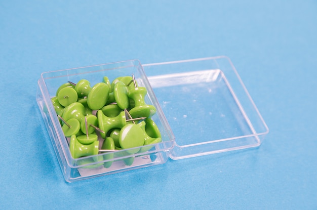 A transparent box of green pushpins isolated