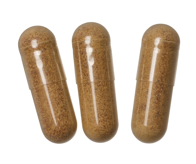 Photo transparent capsule with brown powder on isolated background medical drug top view