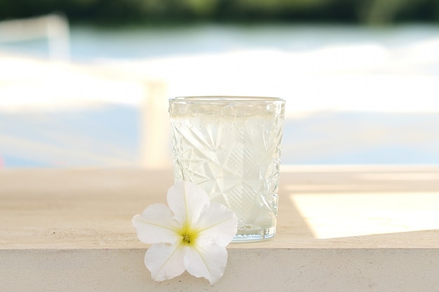 Transparent cocktail in a glass tumbler. lemonade. Flower decor