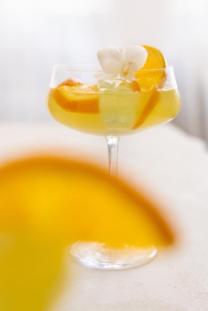 Transparent cocktail with ice cubes in a glass decorated with slices of orange close up